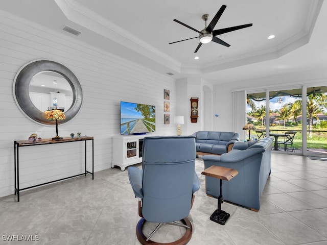 living room featuring ceiling fan, light tile patterned floors, crown molding, and a tray ceiling