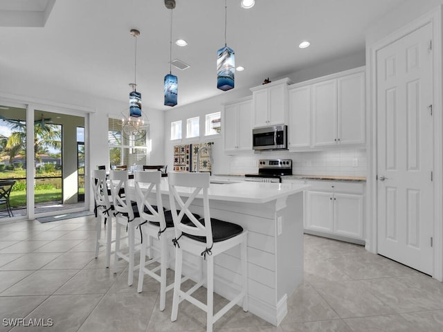 kitchen with white cabinetry, hanging light fixtures, and appliances with stainless steel finishes