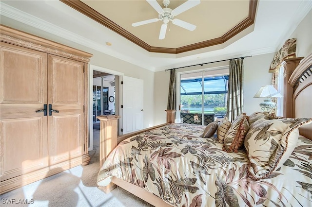 bedroom featuring access to exterior, a tray ceiling, light colored carpet, ceiling fan, and crown molding