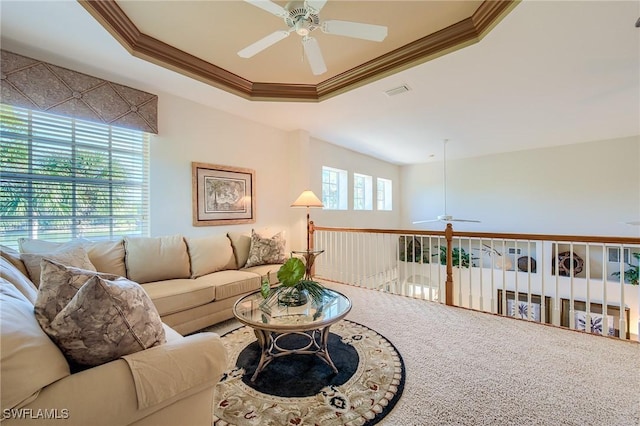 living room featuring ceiling fan, a wealth of natural light, and a tray ceiling