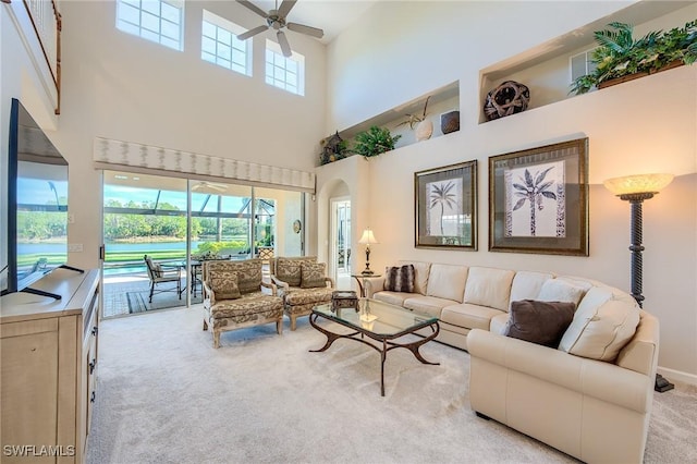 carpeted living room featuring ceiling fan and a high ceiling