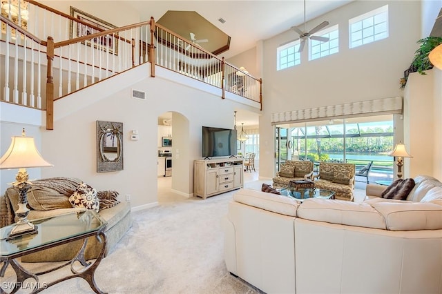 carpeted living room featuring ceiling fan and a high ceiling