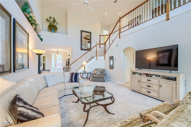 carpeted living room featuring ceiling fan and a high ceiling