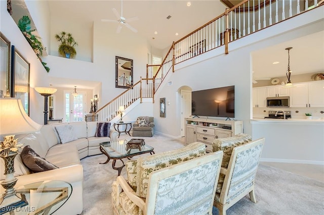 carpeted living room with ceiling fan and a high ceiling