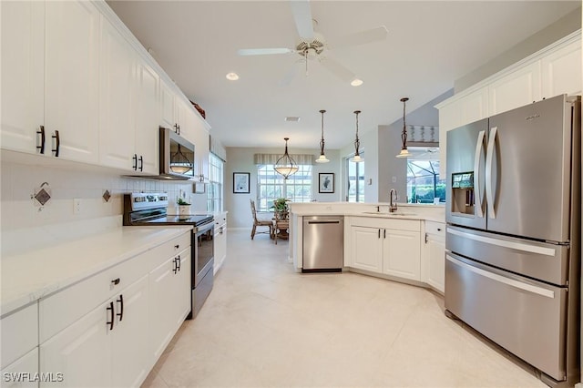 kitchen with appliances with stainless steel finishes, ceiling fan, sink, pendant lighting, and white cabinetry