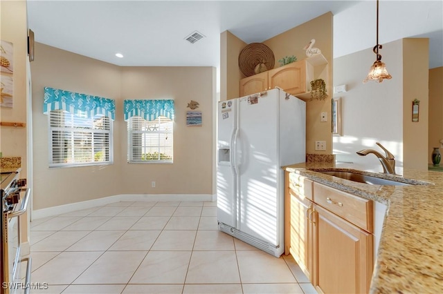 kitchen with sink, light tile patterned floors, light brown cabinets, pendant lighting, and white refrigerator with ice dispenser