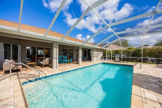 view of pool featuring outdoor lounge area, ceiling fan, a patio, and glass enclosure