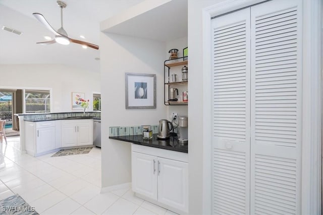 kitchen featuring kitchen peninsula, stainless steel dishwasher, ceiling fan, light tile patterned floors, and white cabinetry