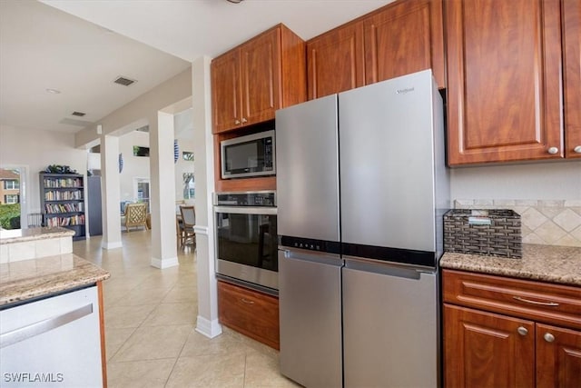 kitchen with light stone countertops, light tile patterned floors, and stainless steel appliances