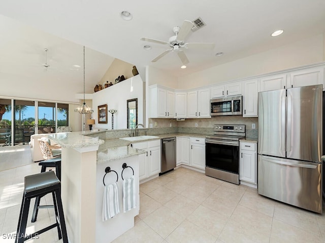 kitchen featuring sink, kitchen peninsula, light stone counters, white cabinetry, and stainless steel appliances