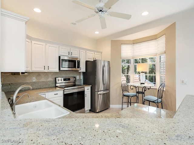 kitchen with white cabinetry, sink, ceiling fan, backsplash, and appliances with stainless steel finishes