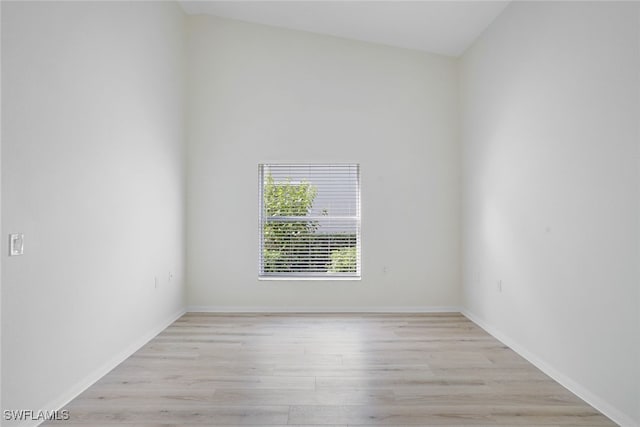 spare room with light hardwood / wood-style floors and lofted ceiling