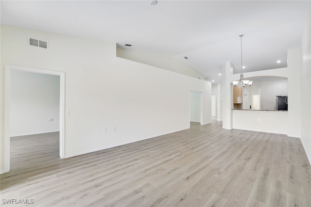 unfurnished living room featuring a notable chandelier, lofted ceiling, and light wood-type flooring