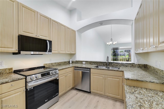 kitchen featuring light stone counters, stainless steel appliances, sink, a notable chandelier, and hanging light fixtures