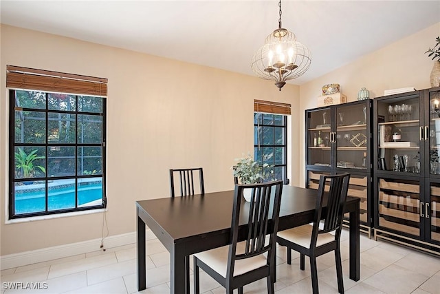 dining room with a healthy amount of sunlight, light tile patterned floors, and an inviting chandelier