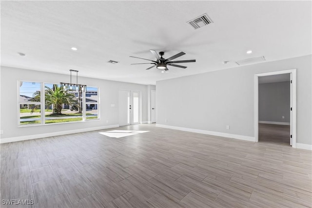 unfurnished living room featuring ceiling fan with notable chandelier