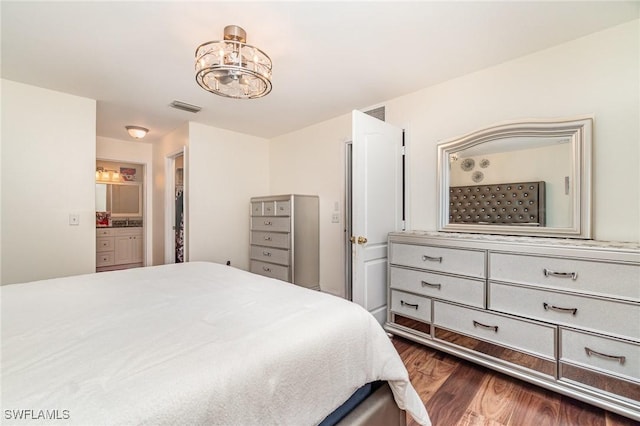 bedroom featuring ensuite bathroom, dark hardwood / wood-style flooring, and an inviting chandelier