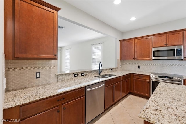 kitchen with light stone counters, sink, appliances with stainless steel finishes, and tasteful backsplash