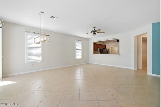 spare room with light tile patterned floors, ceiling fan with notable chandelier, and a healthy amount of sunlight