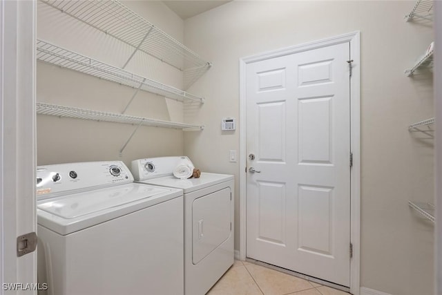 clothes washing area with washer and dryer and light tile patterned floors