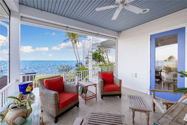 sunroom featuring ceiling fan, a healthy amount of sunlight, and a water view