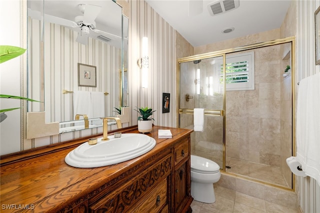 bathroom featuring vanity, a shower with door, tile patterned flooring, ceiling fan, and toilet