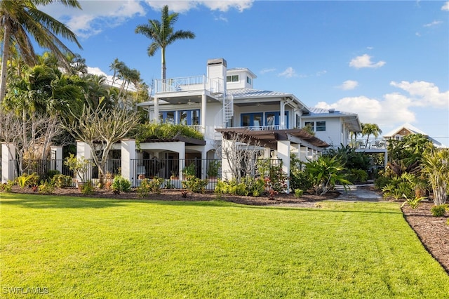 rear view of property with a yard, a pergola, and a balcony