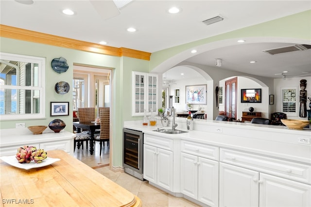 kitchen with light tile patterned floors, white cabinetry, sink, and beverage cooler