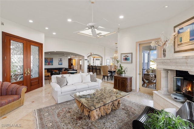 living room featuring a fireplace, ceiling fan, and french doors