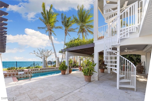 view of patio with a water view, ceiling fan, and pool water feature