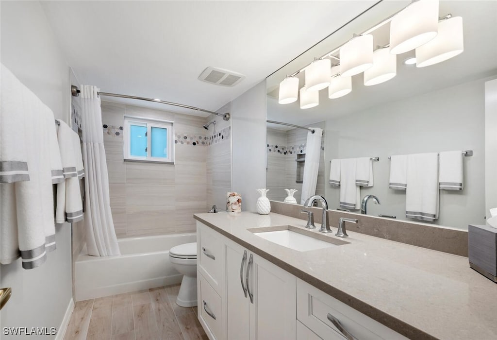 full bathroom featuring hardwood / wood-style floors, vanity, toilet, and shower / bathtub combination with curtain