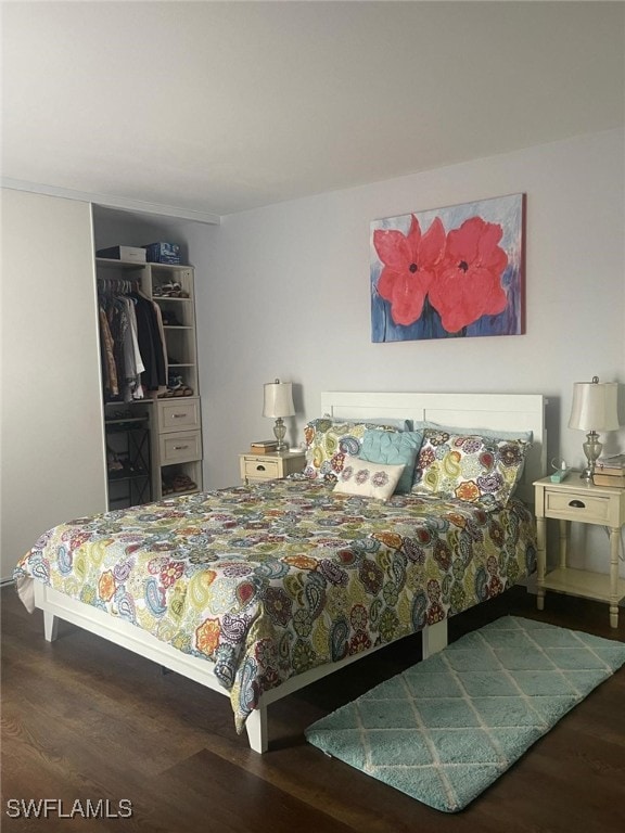 bedroom with dark hardwood / wood-style flooring and a closet