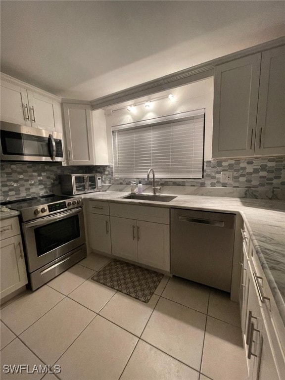 kitchen featuring light tile patterned flooring, appliances with stainless steel finishes, tasteful backsplash, and sink