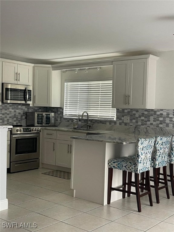 kitchen with a kitchen bar, dark stone countertops, white cabinetry, and stainless steel appliances