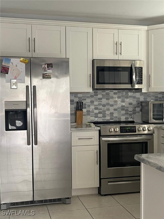 kitchen with light tile patterned flooring, white cabinetry, appliances with stainless steel finishes, and tasteful backsplash