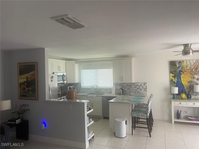 kitchen featuring tasteful backsplash, white cabinetry, a breakfast bar, and stainless steel appliances