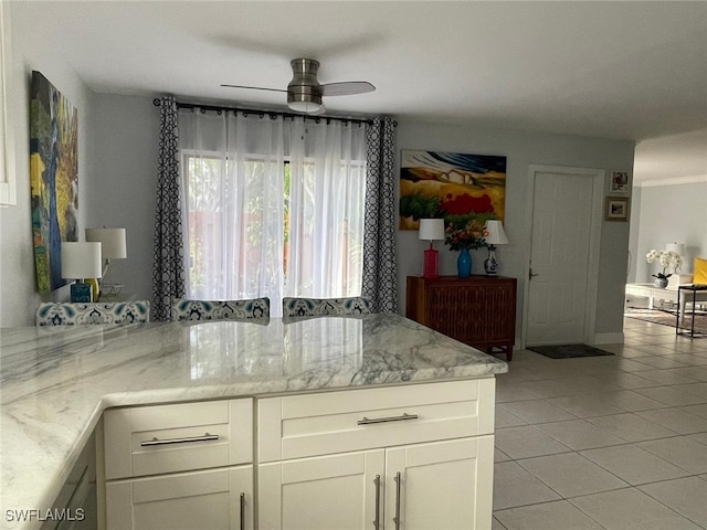 kitchen with light stone countertops, white cabinets, ceiling fan, and light tile patterned flooring