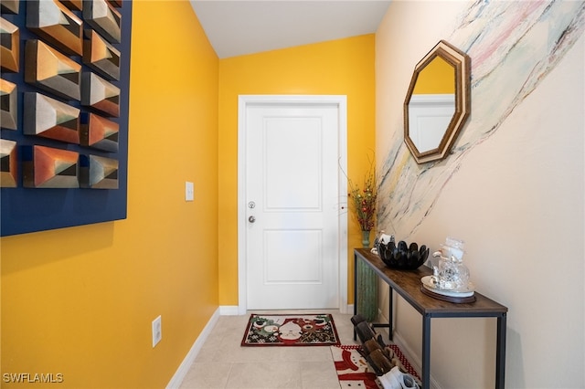 doorway with tile patterned floors and lofted ceiling