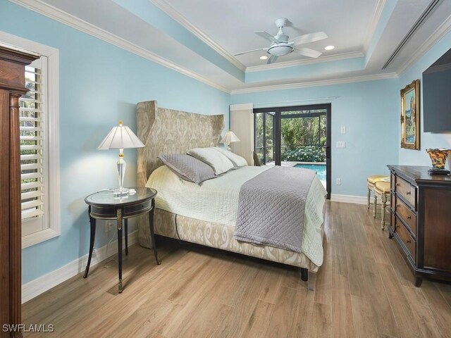 bedroom featuring access to exterior, light hardwood / wood-style flooring, ornamental molding, and a raised ceiling