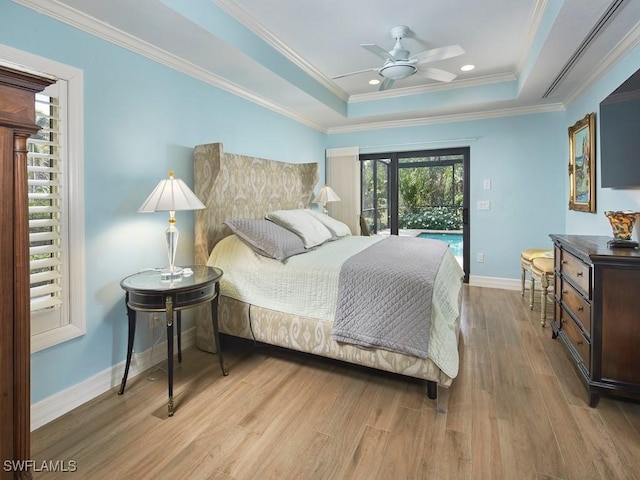 bedroom with a tray ceiling, crown molding, wood finished floors, and baseboards