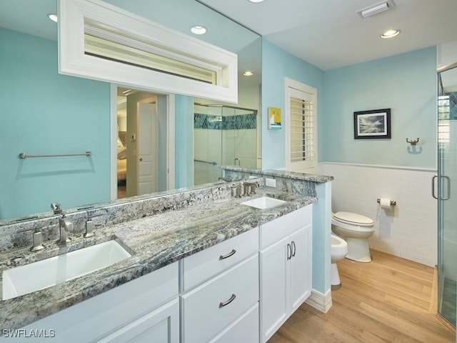 bathroom with a bidet, tile walls, vanity, wood-type flooring, and toilet