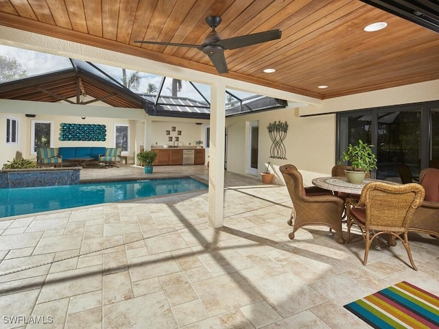 pool with a ceiling fan, glass enclosure, exterior kitchen, outdoor lounge area, and a patio area