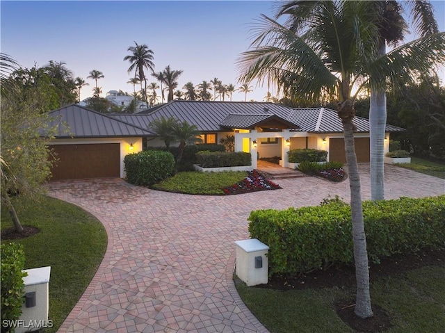 view of front of property featuring stucco siding, a standing seam roof, decorative driveway, metal roof, and a garage