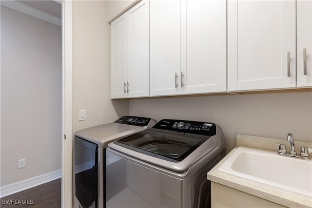 laundry room featuring cabinets, ornamental molding, dark wood-type flooring, sink, and independent washer and dryer