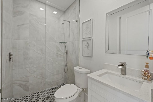 bathroom featuring toilet, vanity, and tiled shower