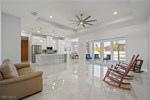 living room with a raised ceiling and ceiling fan