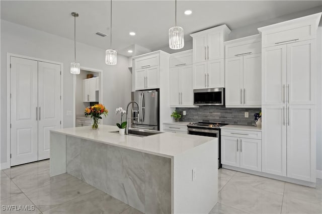 kitchen featuring white cabinets, hanging light fixtures, an island with sink, and stainless steel appliances