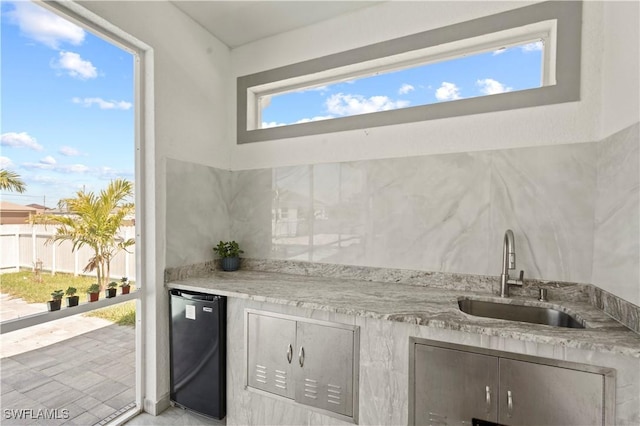 kitchen featuring refrigerator, light stone counters, and sink