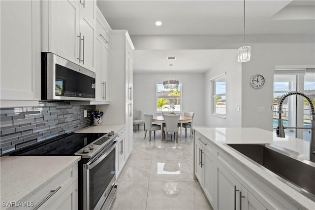 kitchen with appliances with stainless steel finishes, white cabinetry, and pendant lighting