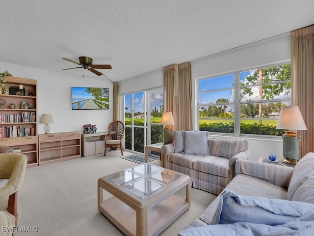 living room featuring ceiling fan, light colored carpet, and a textured ceiling